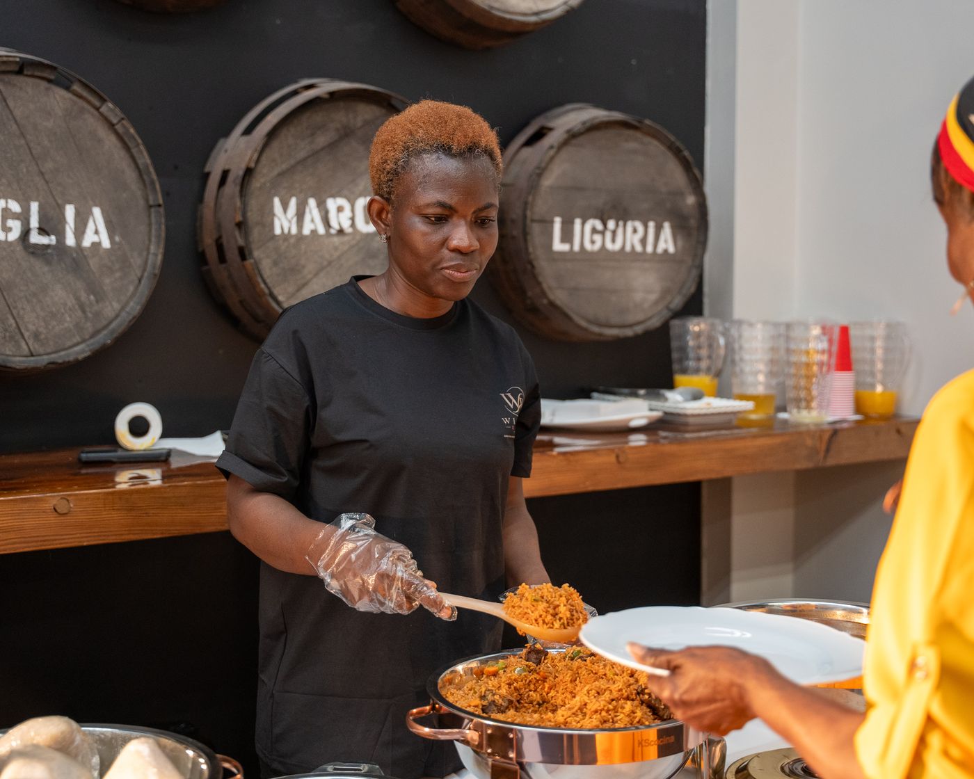 A WillBe Events team member serving jollof rice at a private party
