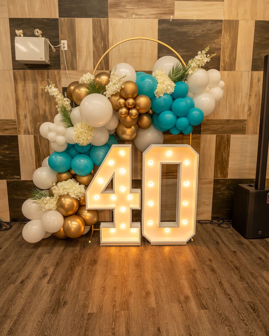 Gold, white and teal balloon arch with lit-up 40 marquee numbers