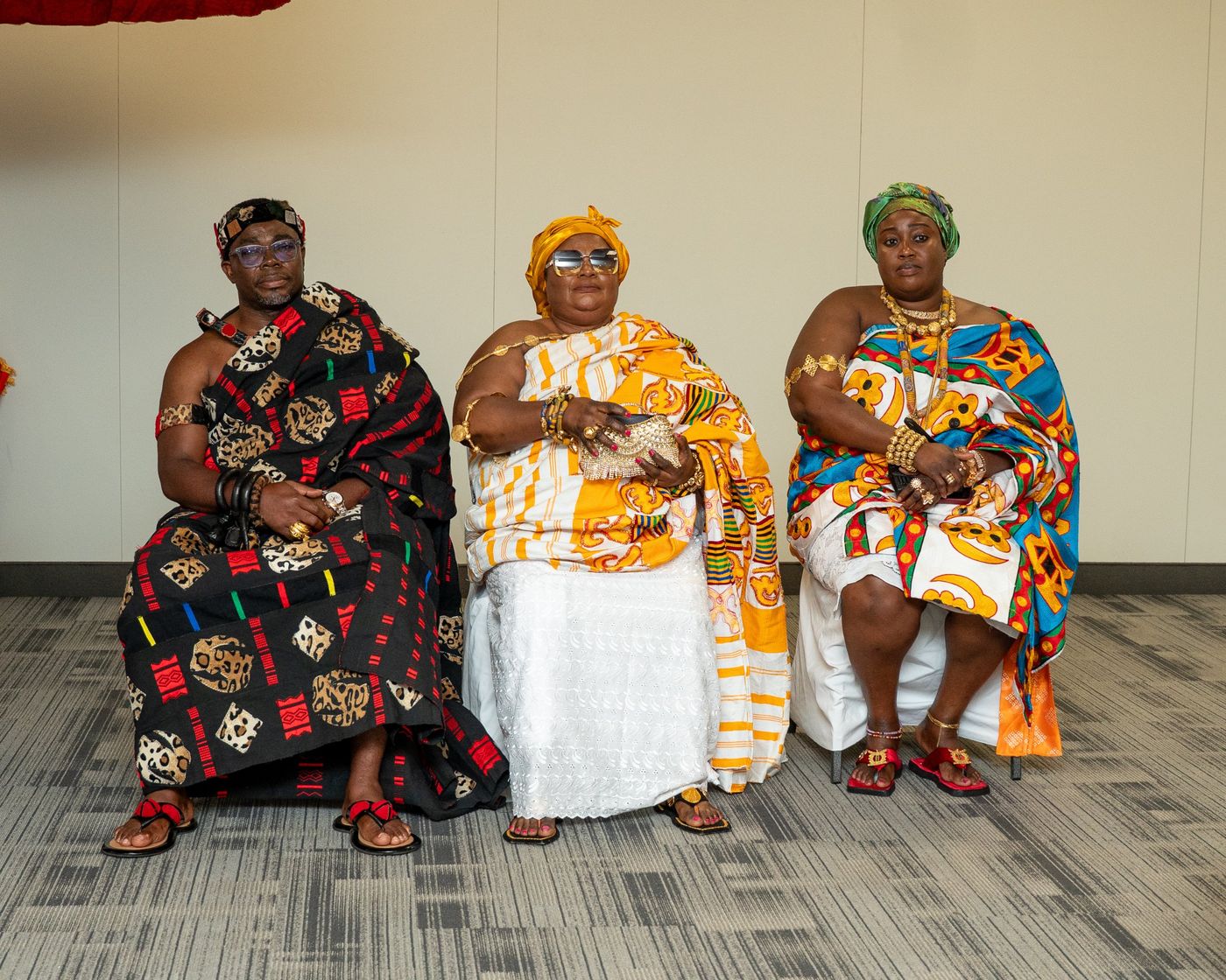 Three royals in kente and gold regalia seated together