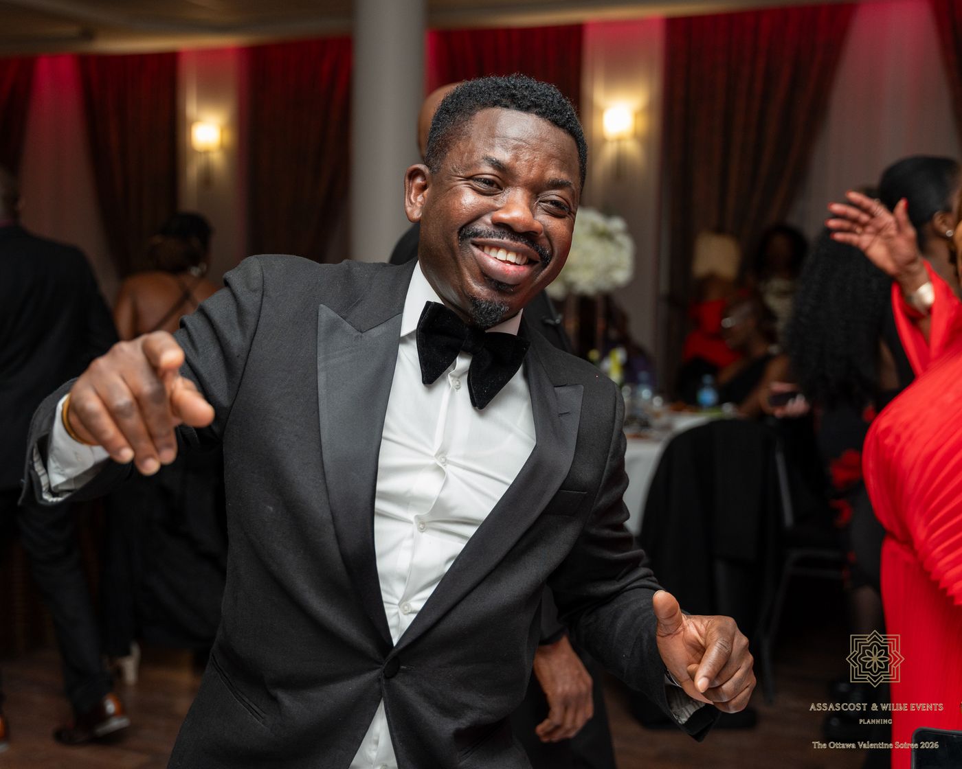 A guest in a tuxedo and bow tie dancing and smiling