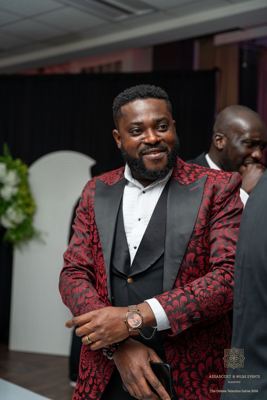 A guest in a red floral tuxedo jacket smiling