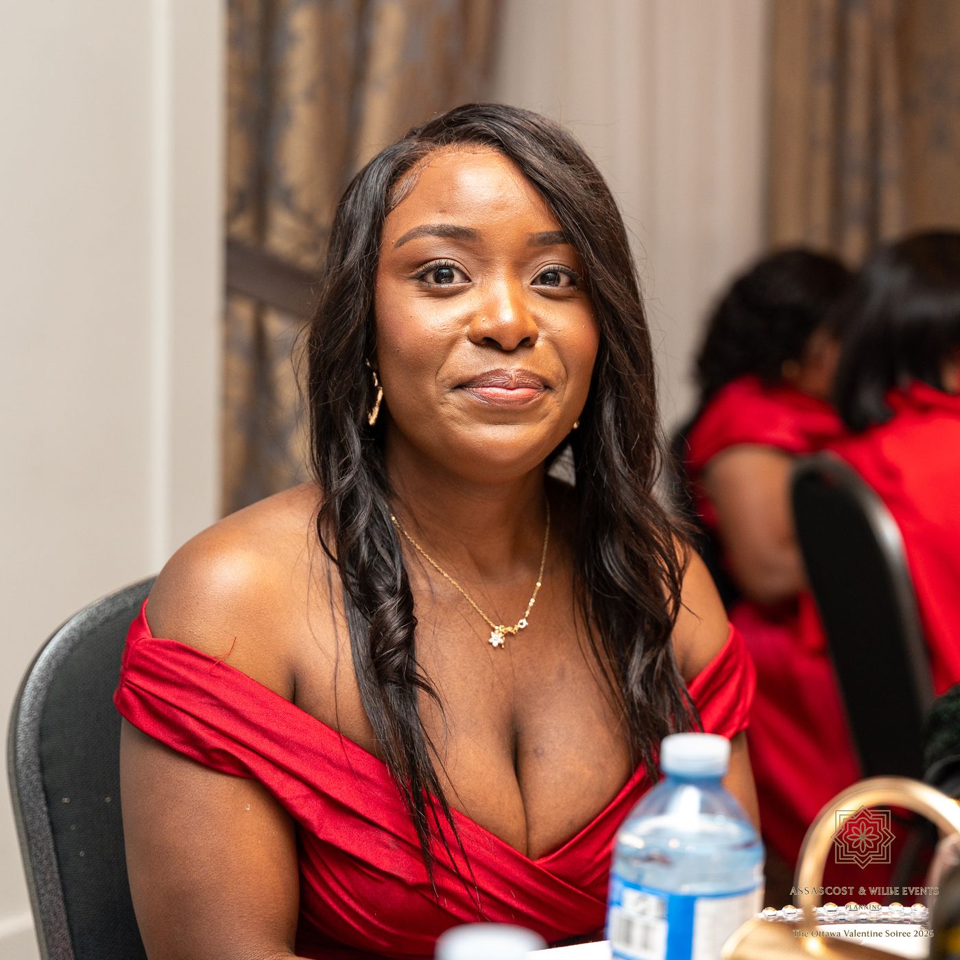 A guest in a red off-shoulder dress smiling at the camera